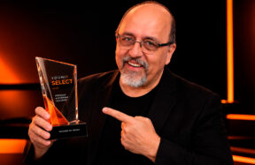 Retrato editorial digital de Érico San Juan segurando o troféu Younik Select em cenário preto com iluminação laranja