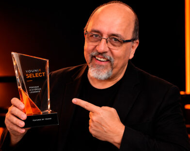 Retrato editorial digital de Érico San Juan segurando o troféu Younik Select em cenário preto com iluminação laranja