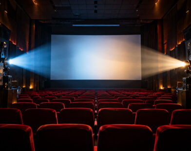 Sala de cinema com poltronas vermelhas e dois projetores, representando a união de grandes estúdios de Hollywood